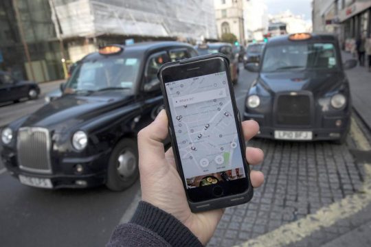 A photo illustration shows the Uber app on a mobile telephone, as it is held up for a posed photograph, with London Taxis in the background, in London, Britain November 10, 2017. REUTERS/Simon Dawson